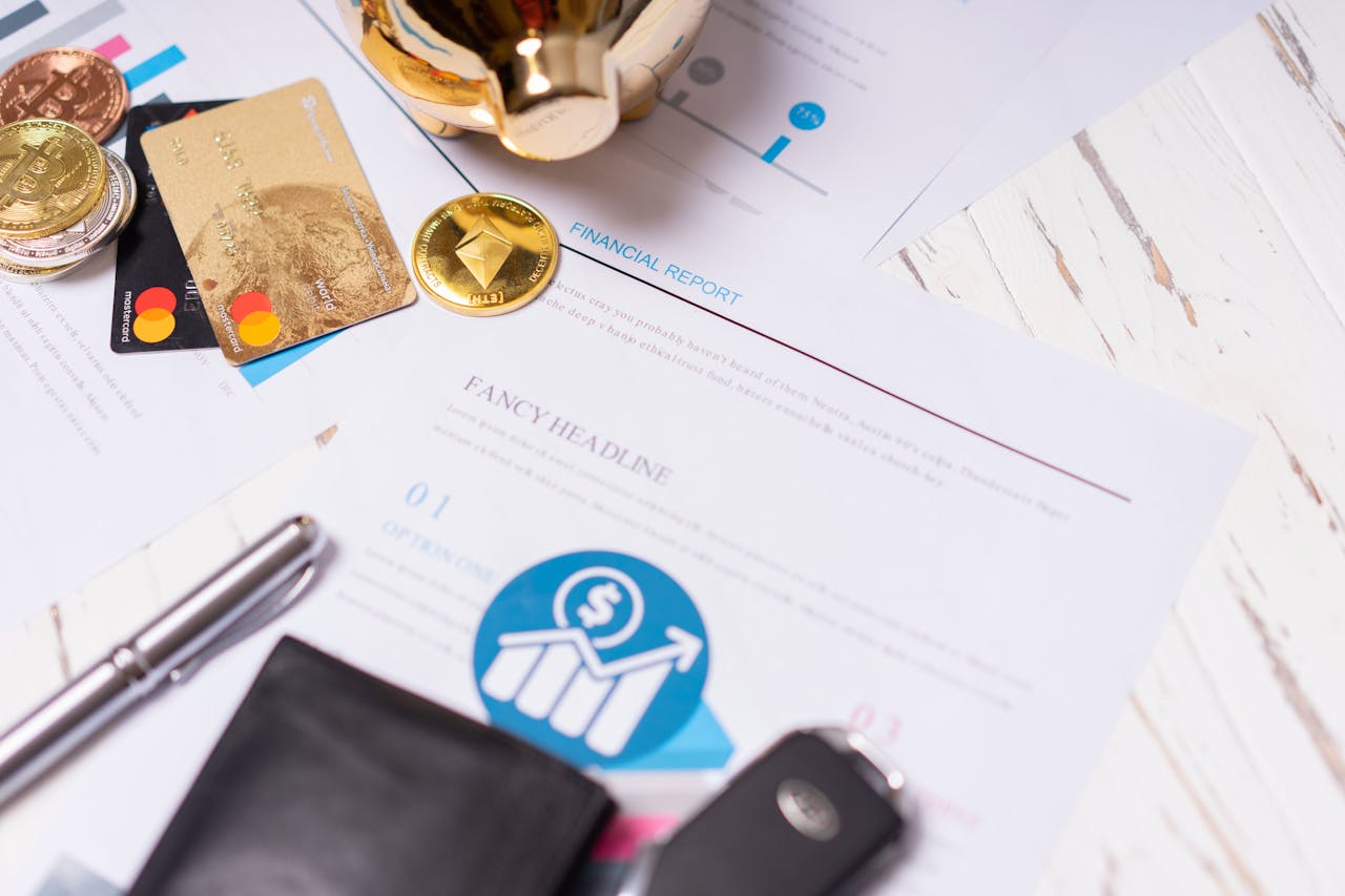 Close-up of financial documents, credit cards, coins, and a pen on a wooden desk.